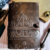 Decorative notebook with embossed design and text 'The Deathly Hallows' on a textured surface.